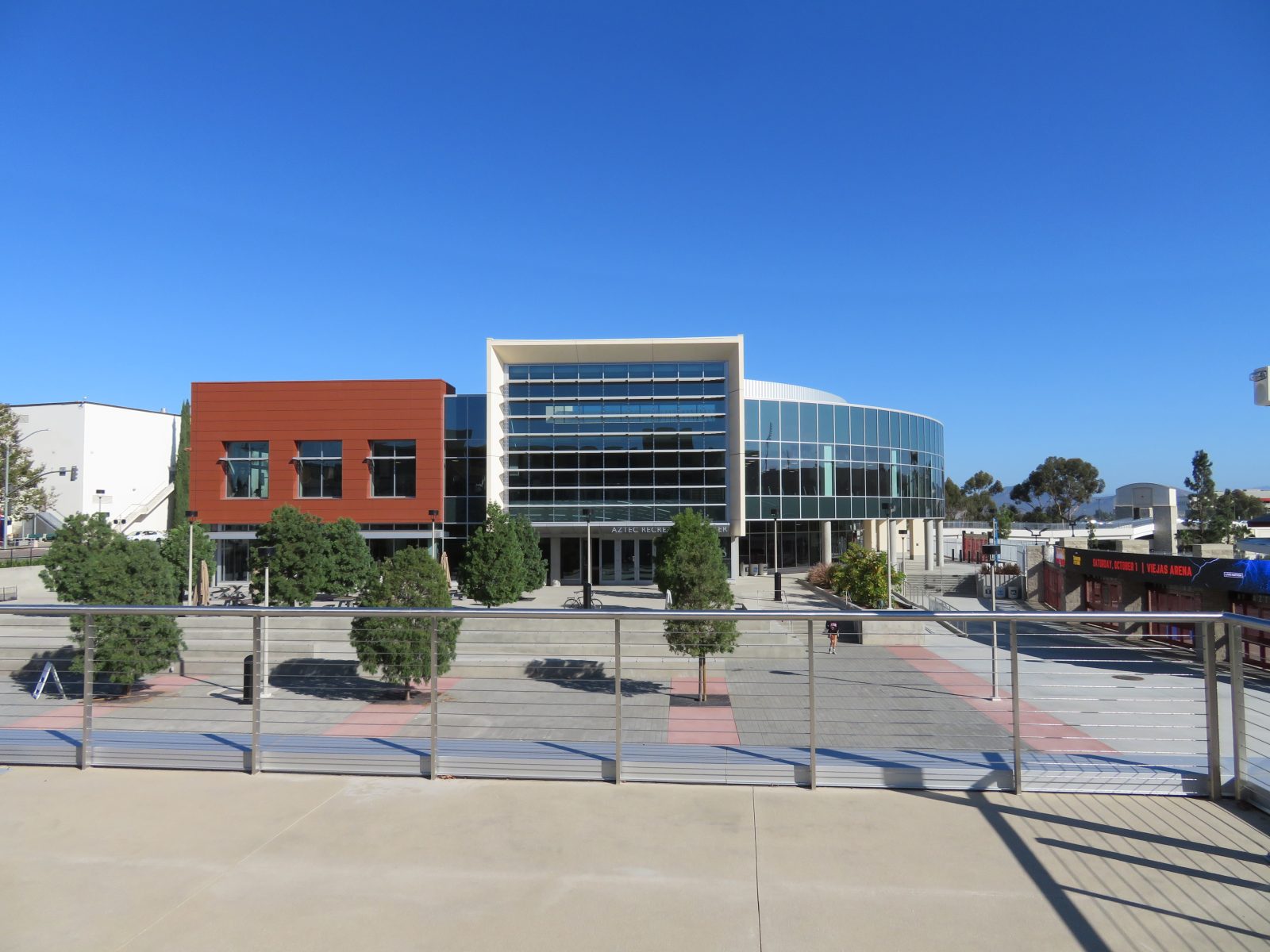 Exterior of the Aztec Recreation Center, featuring modern glass-fronted buildings and a paved plaza