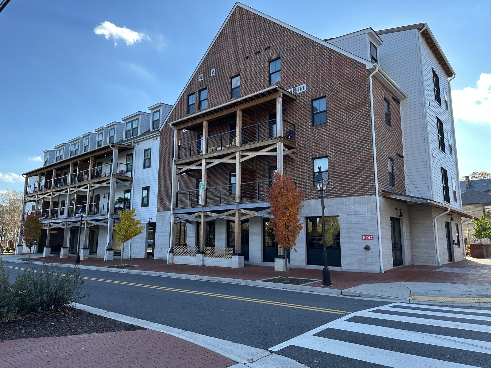 Three-story brick-and-siding building with wooden balconies along a brick-paved street