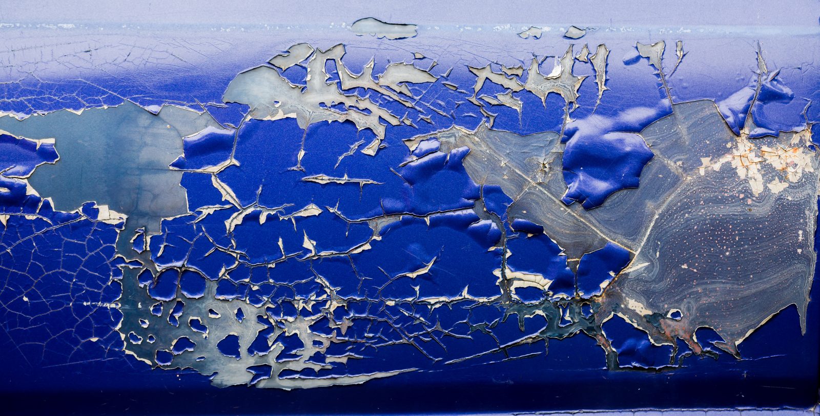 Close-up of old blue car paint broken, crack color of automobile.Car paint cracks, Cracked painted metal surface.